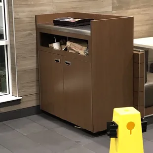 a trash can and a yellow cone