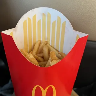 a hand holding a box of french fries