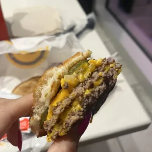 a hand holding a cheeseburger