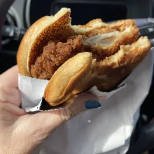 a hand holding a fried chicken sandwich