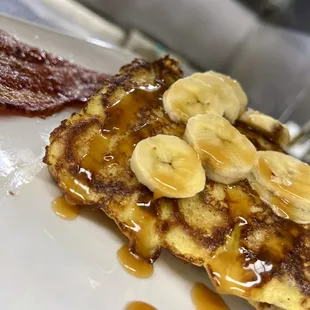 Sweet Wheat Bread French Toast Topped With Banana, House Caramel, Two Strips Of Bacon