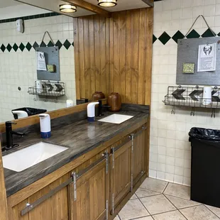 two sinks and a trash can