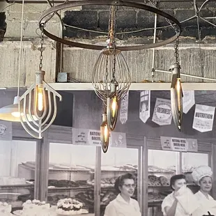 Vintage mixing paddles have been turned into light fixtures in front of a mural photo of their historic business.