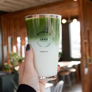 a hand holding a glass of green tea