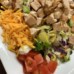 a salad with chicken, lettuce, tomatoes, and cheese