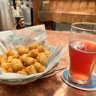 a glass of beer and a basket of fried tater tots
