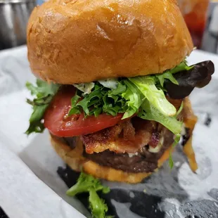 a burger with lettuce, tomato, and bacon