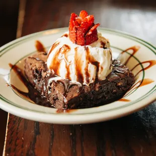 a chocolate brownie with ice cream and strawberries