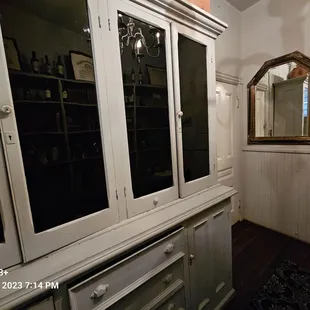 Built into men's bathroom, probably old storage for utensils, plateware and etc to compliment the adjacent kitchen.