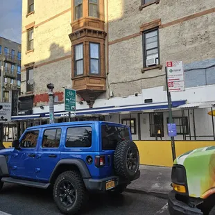 a blue jeep parked in front of a building