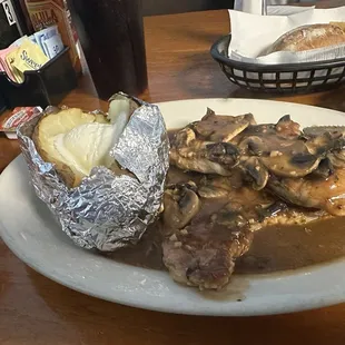Boneless pork chops with baked potato and mushroom gravy.