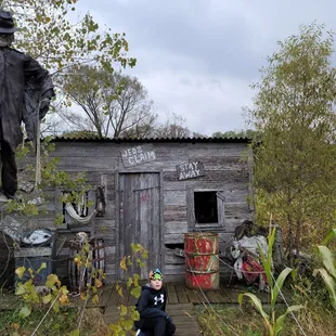 a young boy standing in front of a shack