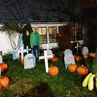 a man standing in front of a graveyard with pumpkins and gourds