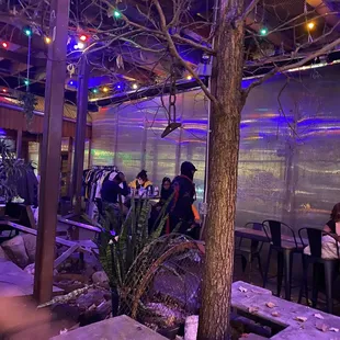 people sitting at tables under a tree