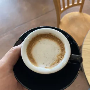 a hand holding a cup of espresso