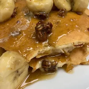 a plate of pancakes with bananas and syrup