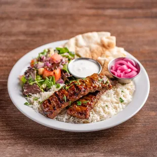 Adana Kebab Plate with basmati rice, house salad, pita bread slices, your choice of in-house made sauce and pickled red onions.