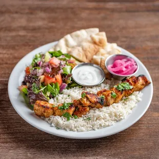 Chicken kebab plate with basmati rice, house salad, pita bread slices, your choice of in-house made sauce and pickled red onions.