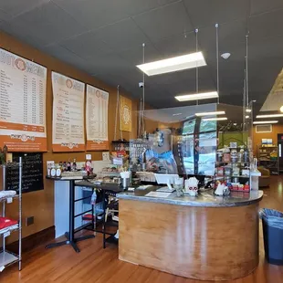 Inside coffee shop. Plenty of seating. A lot of personality and local paintings on the wall. Peaceful and homey feel.