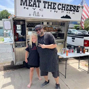 a man and a woman standing in front of a food truck