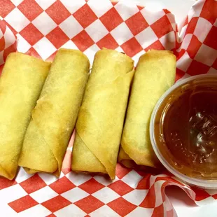 a plate of fried spring rolls with dipping sauce