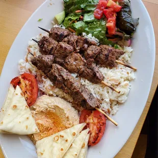 Lamb Kabob Plate with salad, three kabobs, rice, hummus and pita bread, roasted tomatoes, and above average salad.
