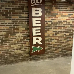 a cold beer sign on a brick wall