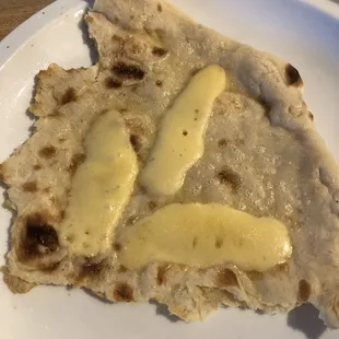 A bit of the massive flat bread we bought with some cheese on it. That's maybe 1/4 of one piece and that's a full-sized dinner plate!