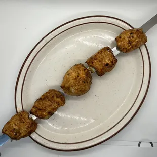 a skewer of meatballs on a plate
