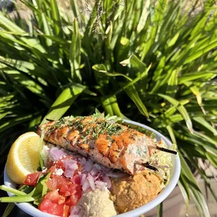 Salmon bowl with hummus, fire feta, coleslaw, and salad.