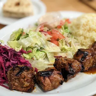 Shlsh Kebab (Lamb-5 pieces) Plate with pickled cabbage, salad, mediterraneean rice.  Pita bread (in background)