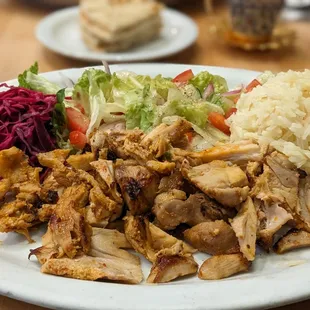 Chicken Gyros Plate with pickled cabbage, salad, mediterraneean rice and a side of yogurt sauce (?).  Pita bread (in background).