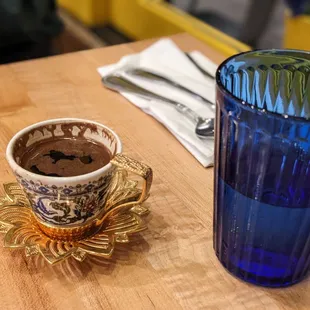 Turkish coffee (L) next to water glass.