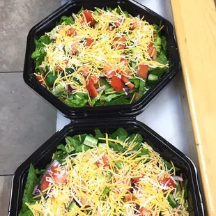 three trays of salad with cheese and tomatoes
