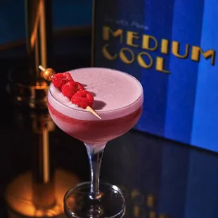 a cocktail with raspberry garnish