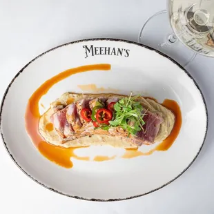 Melt-in-your-mouth Seared Ahi Tuna over a bed of Japanese sweet potatoes finished with a jalapeño ponzu .