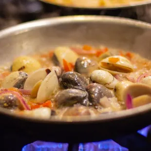 two pans of food cooking on the stove