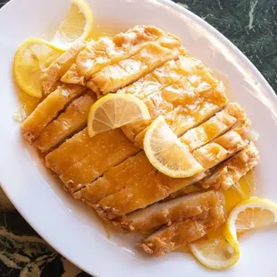 a plate of sliced chicken with lemons