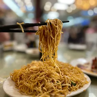 a plate of noodles with chopsticks