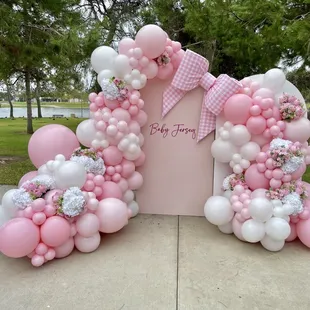 Pink outdoor baby shower backdrop with florals and croquet bow  hosted at  outdoor park