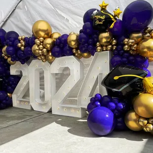 Graduation them with Marquee number rentals with organic balloon garland