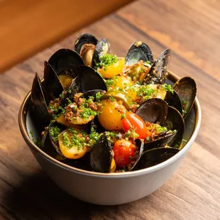 a bowl of steamed musselling on a wooden table