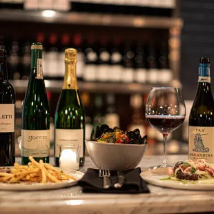a table with wine bottles and plates of food