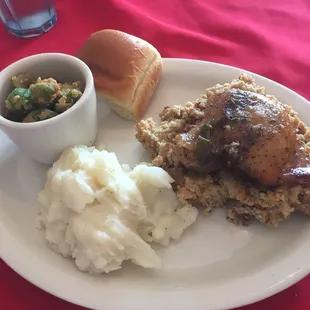 Chicken and dressing with cream potatoes, fried okra, and roll.