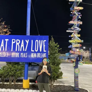 a woman standing in front of a eat pray love sign