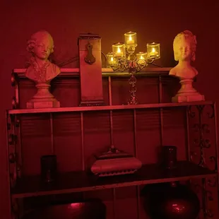 a shelf with candles and busts