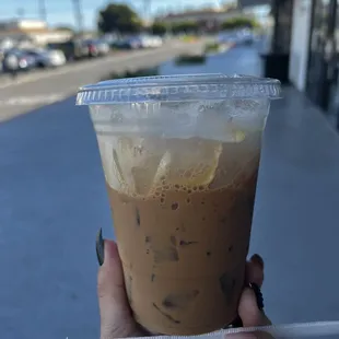 a hand holding a cup of iced coffee