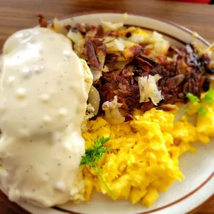 Home fries, scrambled eggs, sausage patties on biscuits with gravy