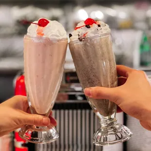 two people toasting with milkshakes