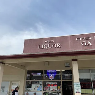 two men sitting outside a liquor store